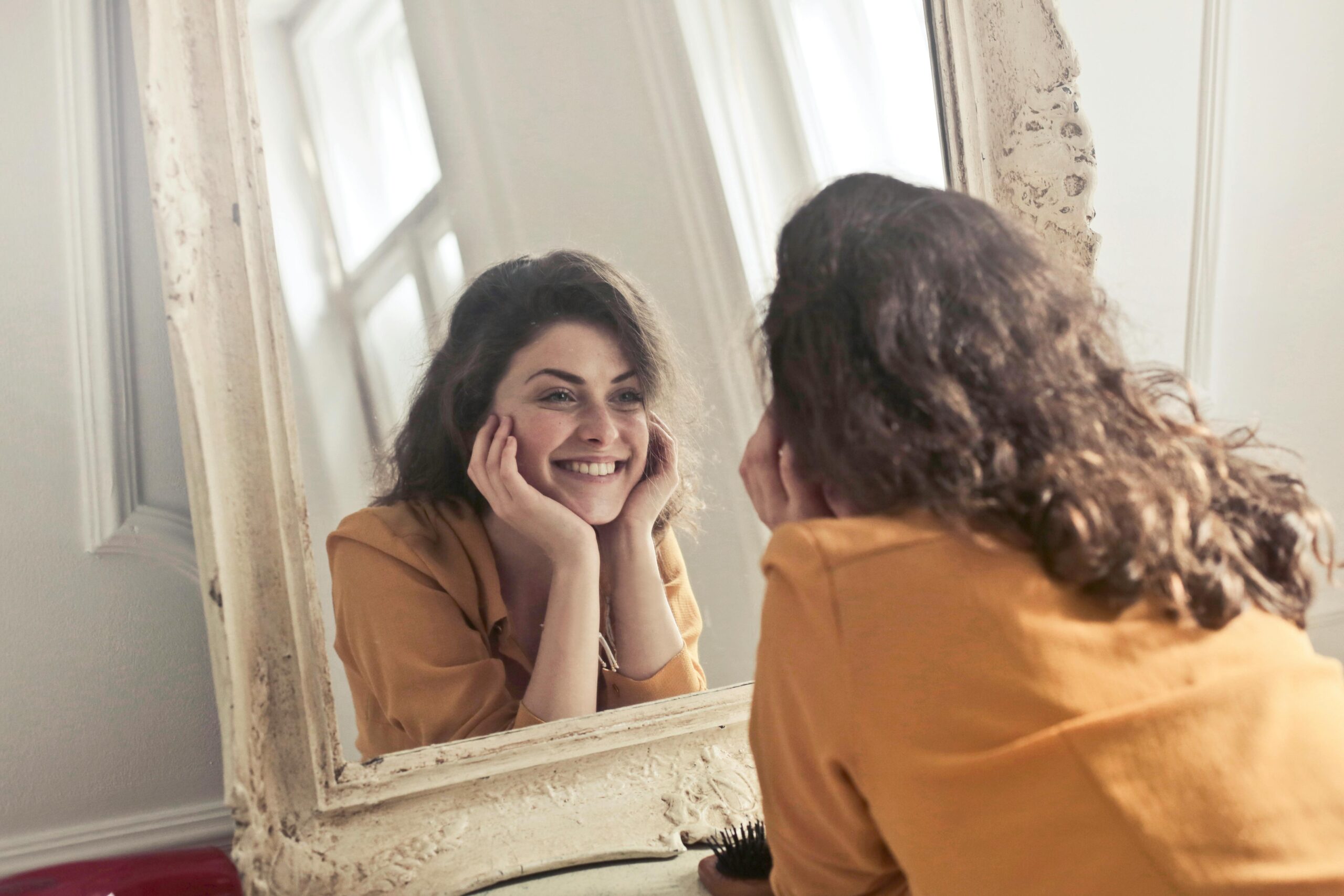 woman smiling and looking at herself in a mirror after restorative dentistry in nyc